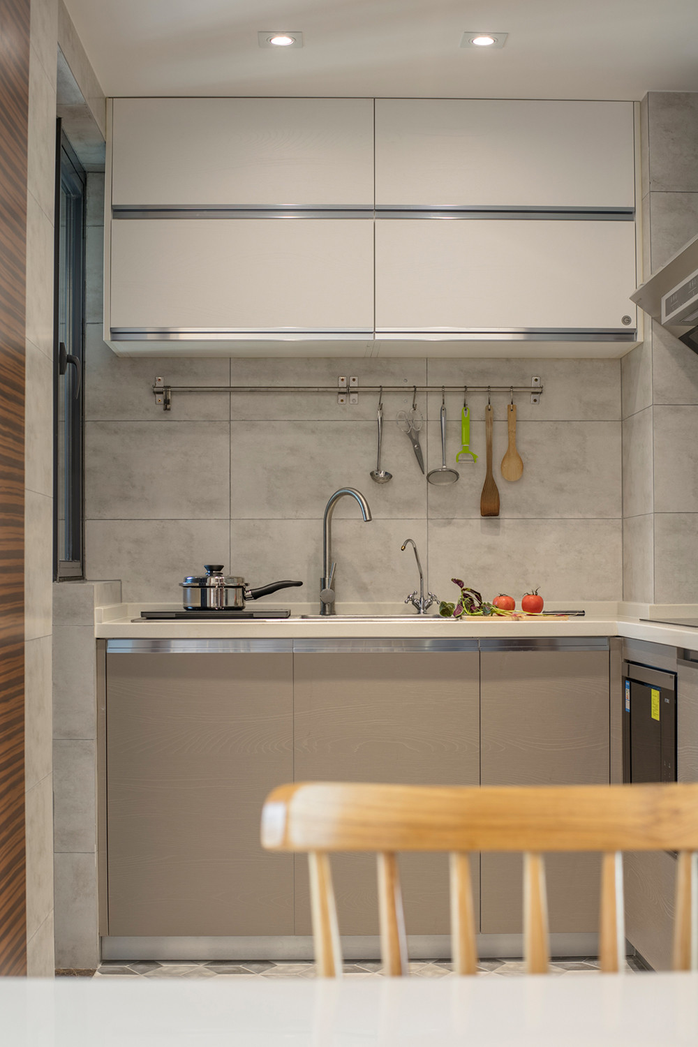 厨房的自然光线透过窗户舒缓地洒入厨房空间，烹饪用具根据平时使用习惯进行收纳。不拘一格的吊灯设计进行点缀，将纯粹的照明功能巧妙地转化为装饰的主角，赋予空间更多元的趣味性。