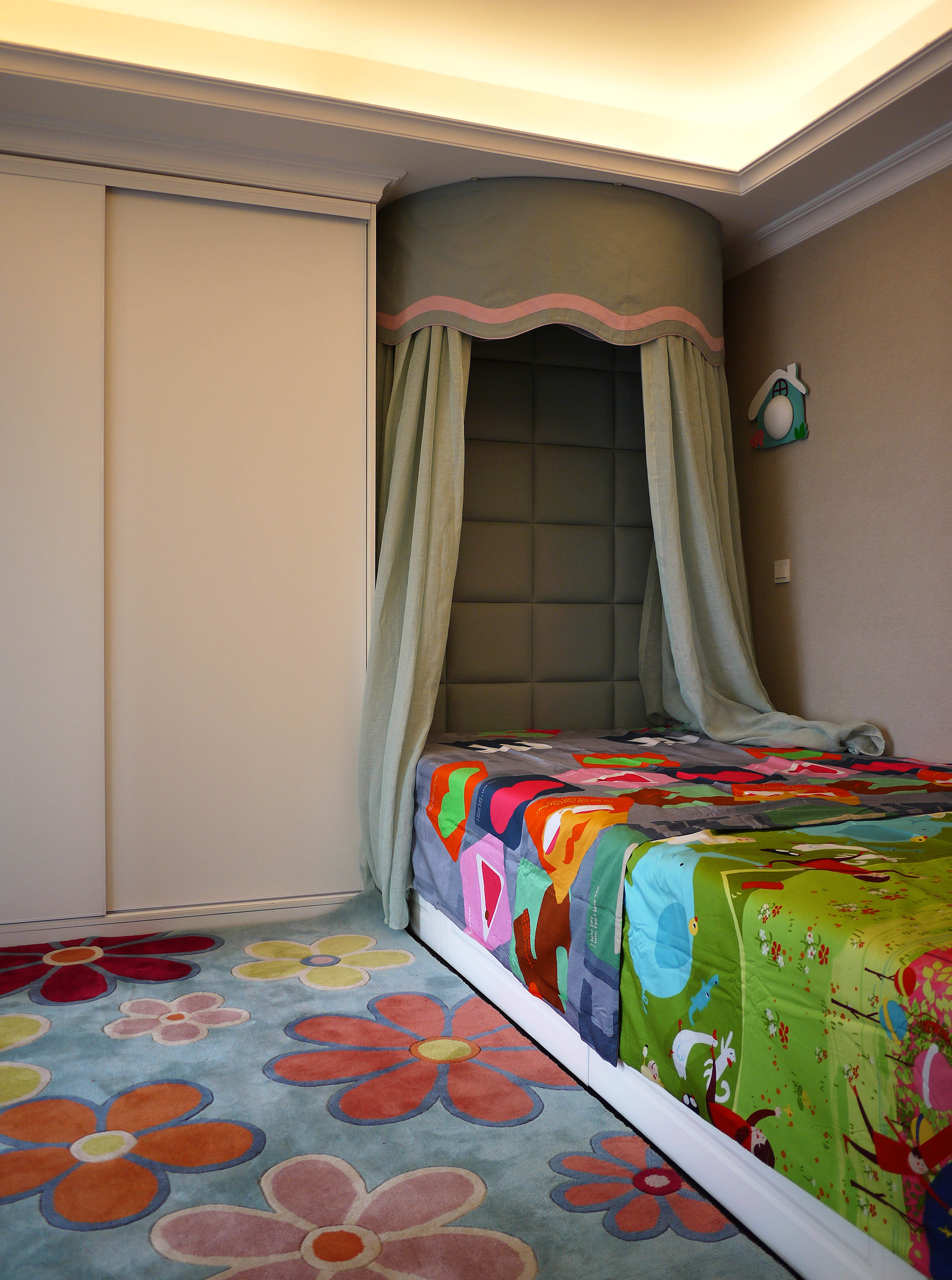 女孩房采用精致小巧的软装设计，地面铺上了有色彩搭配的花式地毯，床单也选用了小碎花图案，让房间温馨又梦幻，为小公主营造一个可爱的成长环境。