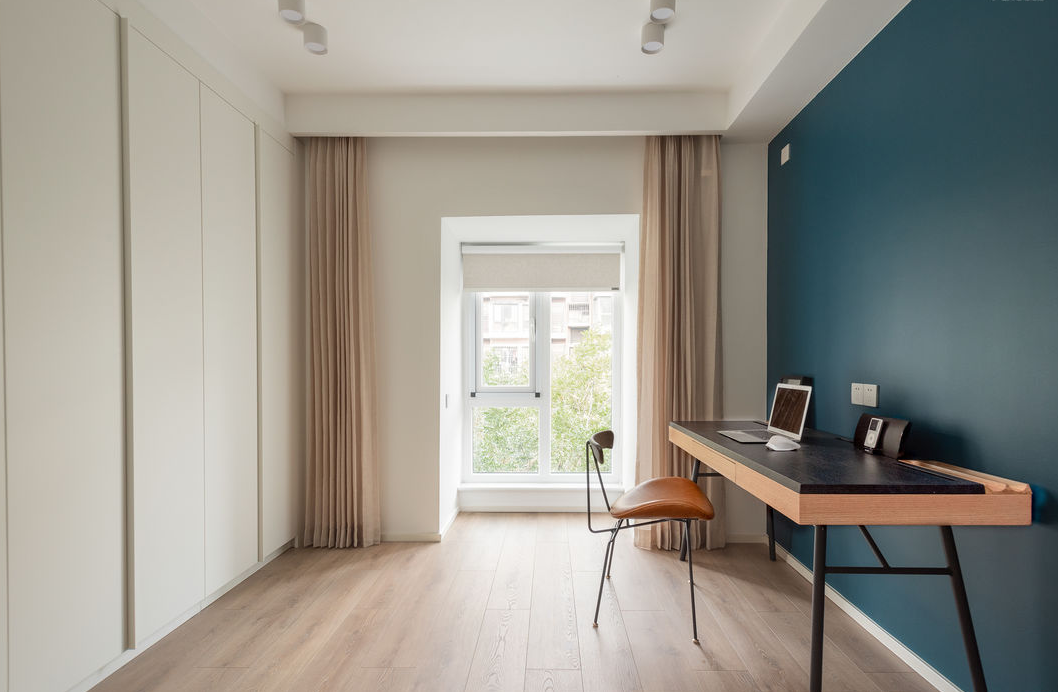 书房不一面墙采用蓝色调，与木质元素搭配，采用原木书桌，打造了一个看书休憩空间。