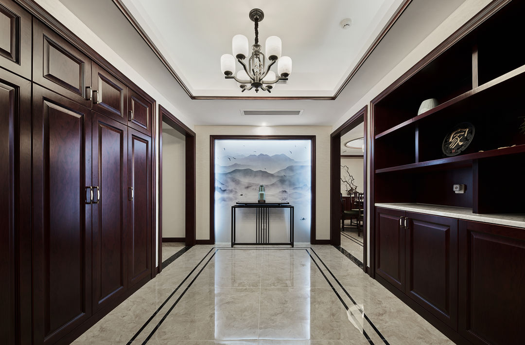 这套家居采用新中式的设计，玄关入户即是衣服水墨画，深棕色的桌面与客厅的家具呼应，营造了一个充满复古、沉稳又温馨的家。